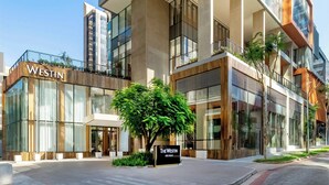 Un hotel moderno con un evidente cartello 'WESTIN', ampie vetrate e un’area esterna curata con alberi.