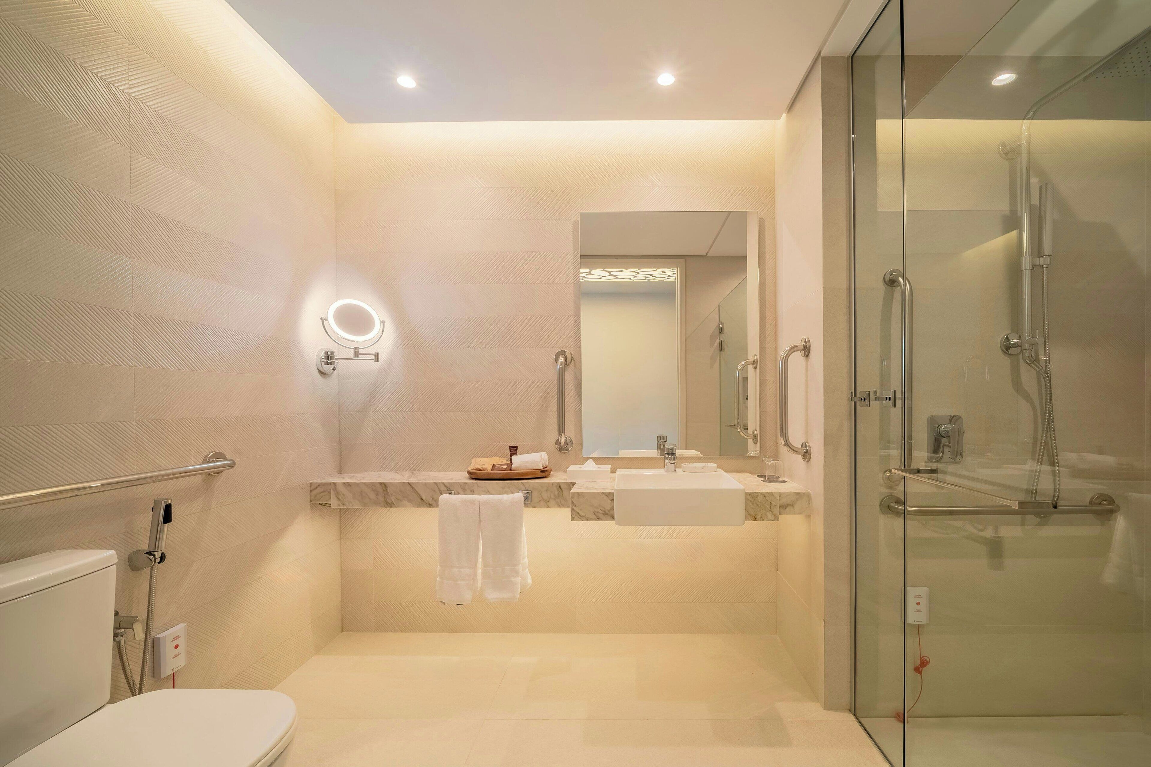 Un baño moderno con cabina de ducha de vidrio, inodoro, lavabo con tocador y espejo.