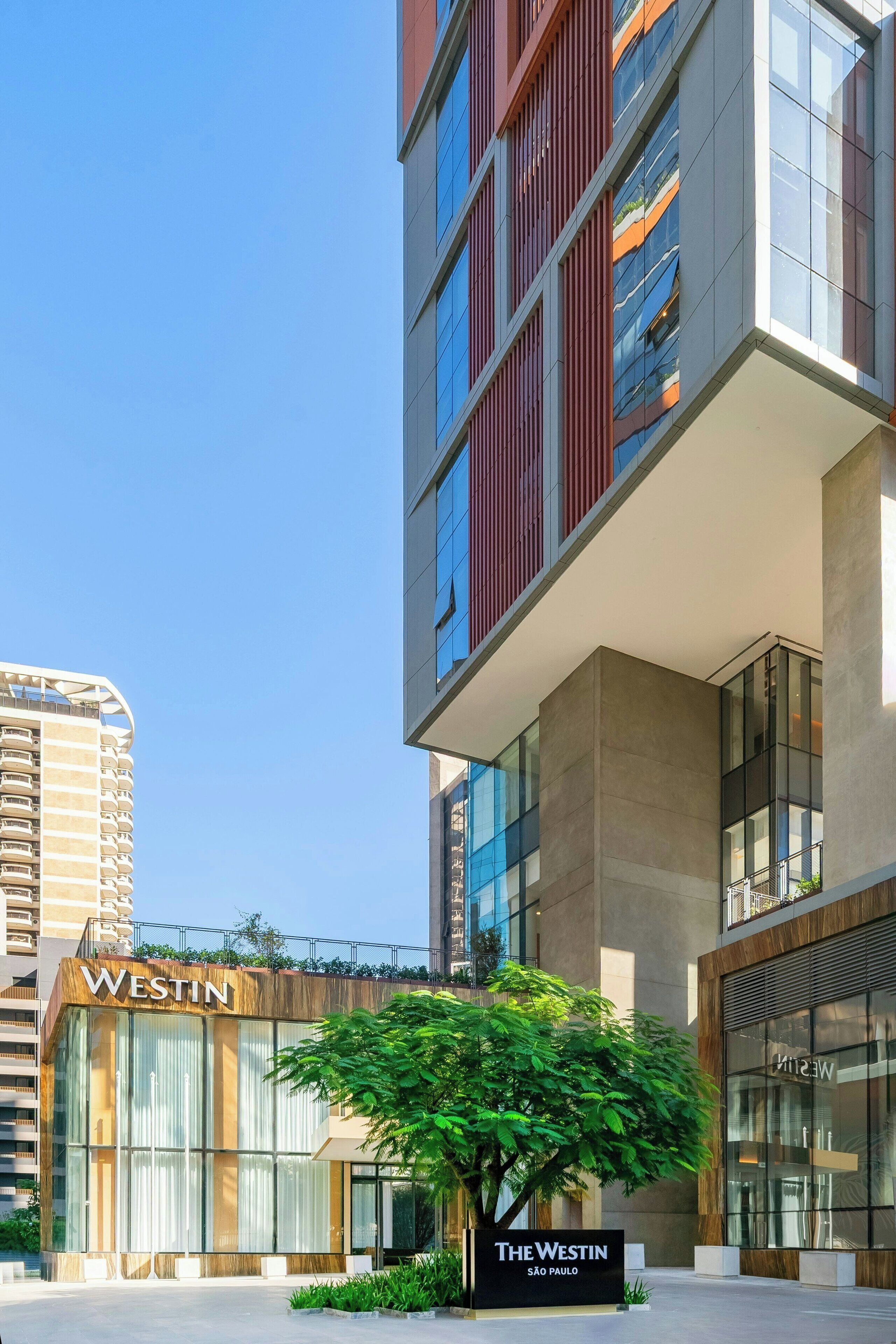 A modern building with a prominent 'The Westin' sign, large windows, and a tree in the foreground.