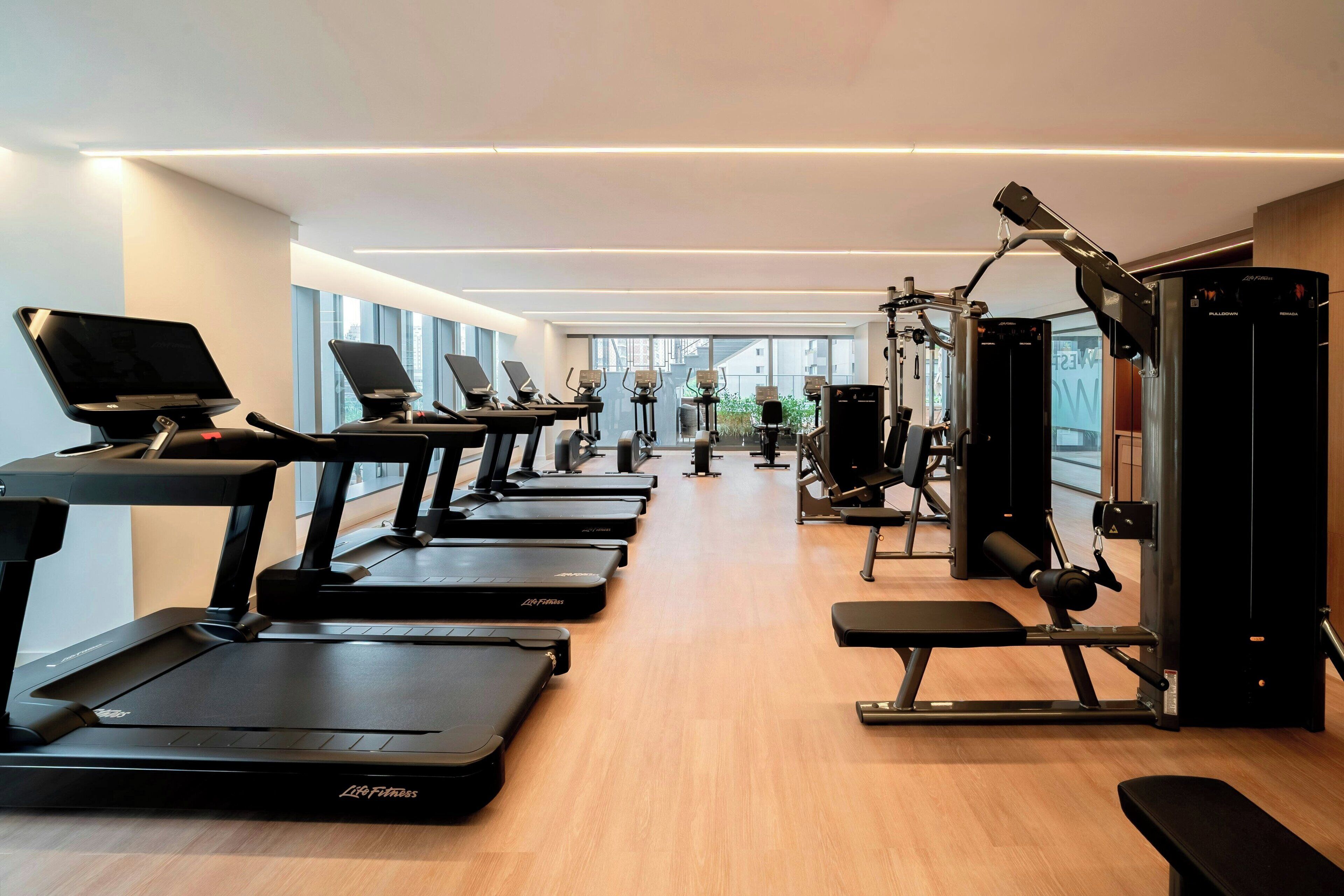 Una palestra con tapis roulant, macchinari per pesi e una panca.