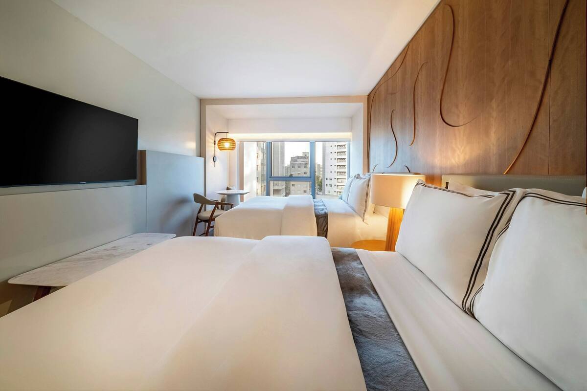 Ein Hotelzimmer mit einem großen Bett, einem Schreibtisch und Blick auf die Stadt.