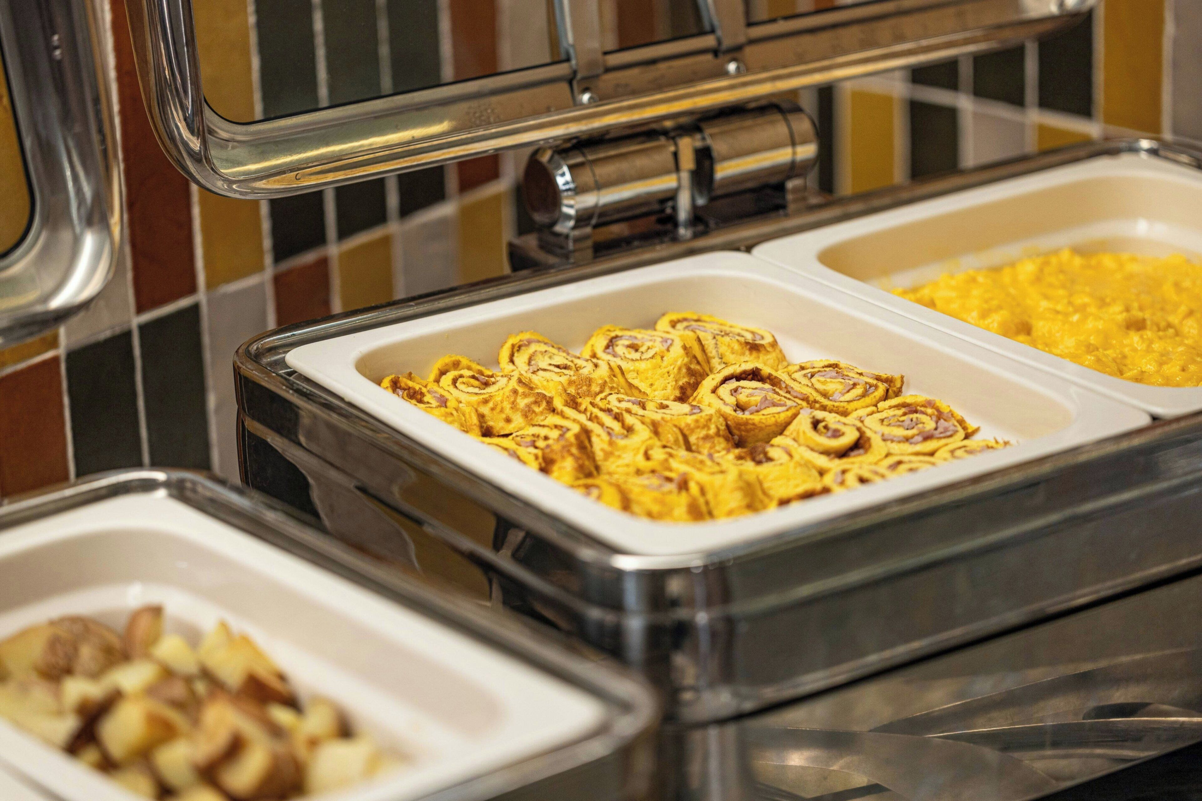 Un bufé con diversos platos de comida presentados en recipientes transparentes.