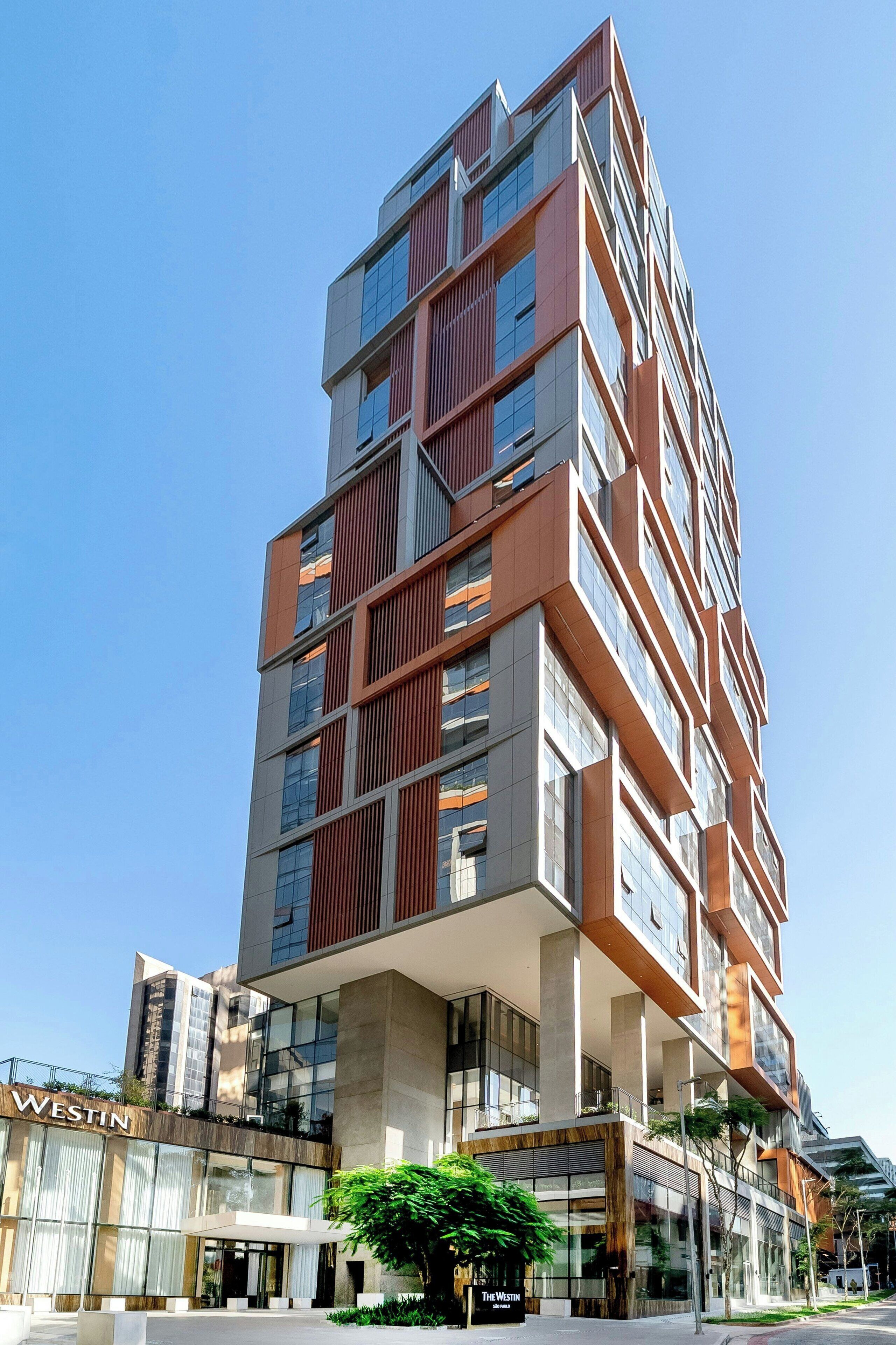 Un moderno edificio de gran altura con un llamativo letrero de 'WESTIN', que presenta una fachada de vidrio y metal, y una entrada visible con marquesina.
