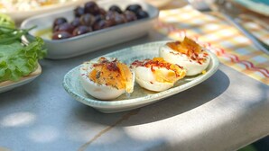 A table with various food items including eggs, olives, and greens, set outdoors. - MAKİA OTEL (Marmaris)