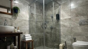 A modern bathroom with a glass-enclosed shower, a sink, a toilet, and a mirror. - MAKİA OTEL (Marmaris)