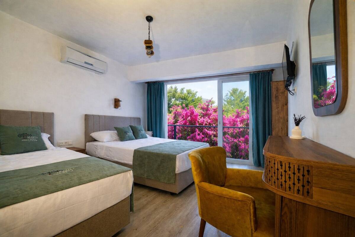 A hotel room with two beds, a wooden desk, a chair, a TV, and a balcony with pink flowers.