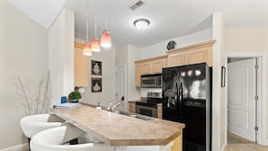 A modern kitchen with a granite countertop, stainless steel appliances, and a white island with bar stools.