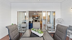 A covered patio area with a table and chairs, a fan, and a view into the house.