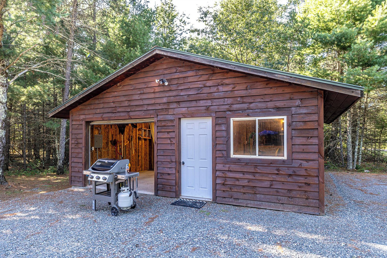Une cabane en bois avec une porte de garage, une porte et une fenêtre.