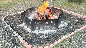 Un hogar circular con leña, rodeado por un borde de grava y un borde de ladrillo.