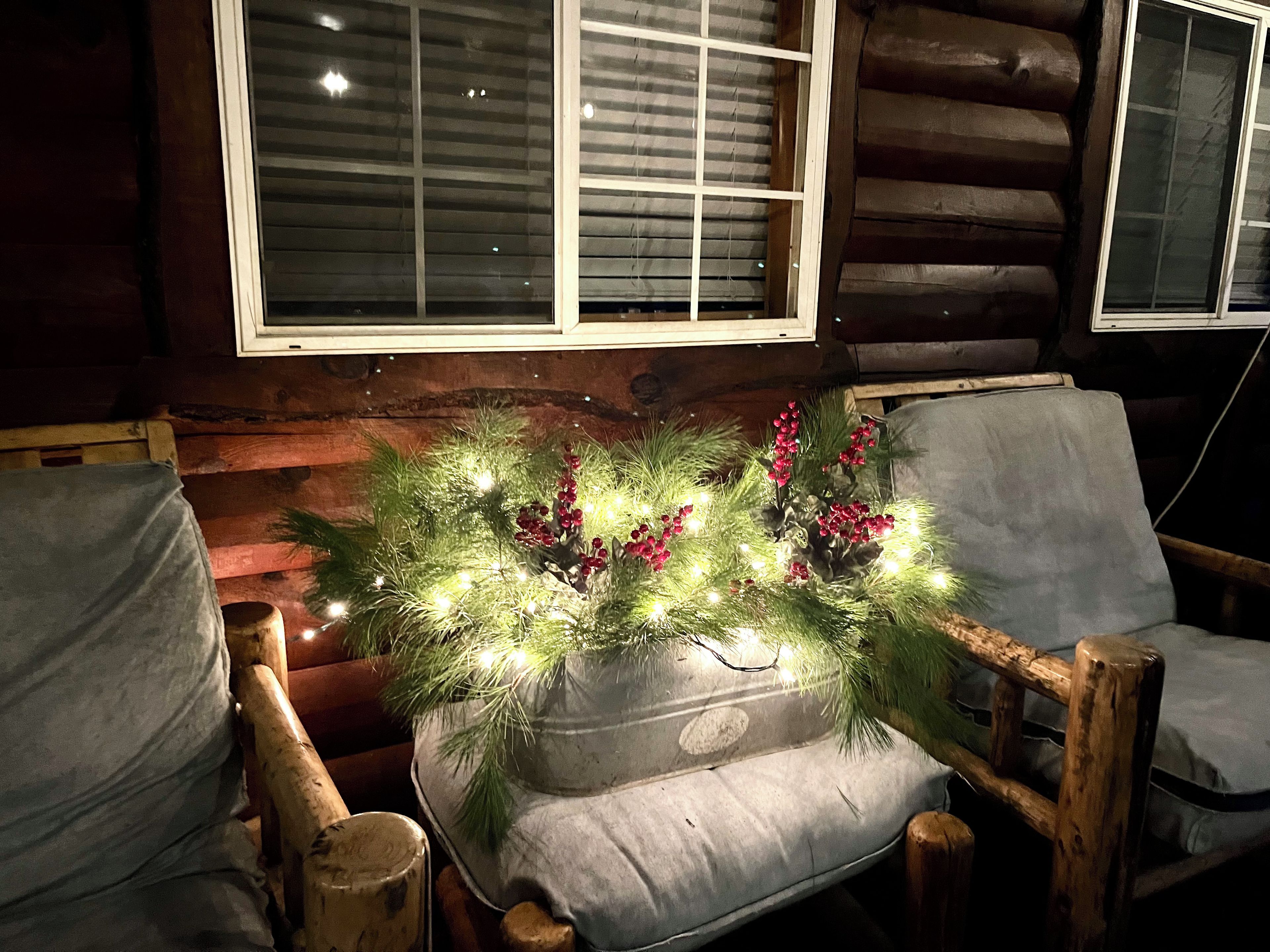 A cozy cabin interior with a wooden bench, a cushioned seat, and a window with blinds.