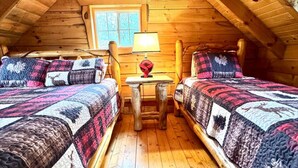 Ein gemütliches Schlafzimmer im Dachgeschoss mit zwei Betten, einem kleinen Tisch und einem Fenster.