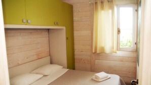 A single bed with a white mattress and pillows, a yellow wardrobe, and a window with curtains. - Little house by the sea (Licinella-Torre di Paestum)