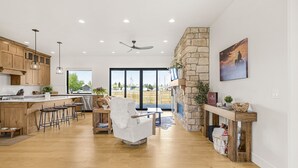 Une cuisine spacieuse avec des meubles en bois, une chaise blanche et une cheminée en pierre.