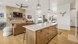 Une cuisine moderne avec une cheminée en pierre, des armoires en bois et des luminaires suspendus.