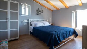 A bedroom with a bed, a wardrobe, and a window. - Stone House Bay View - Kaštel Lukšić (Kastela)