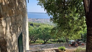 A stone building with a view of a coastal town and olive trees. - Stone House Bay View - Kaštel Lukšić (Kastela)