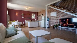 A modern living room with a sofa, a coffee table, and a TV displaying a music video. - Stone House Bay View - Kaštel Lukšić (Kastela)