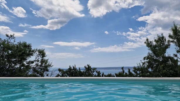 A clear blue pool with a view of the sea and distant land under a partly cloudy sky. - Stone House Bay View - Kaštel Lukšić (Kastela)