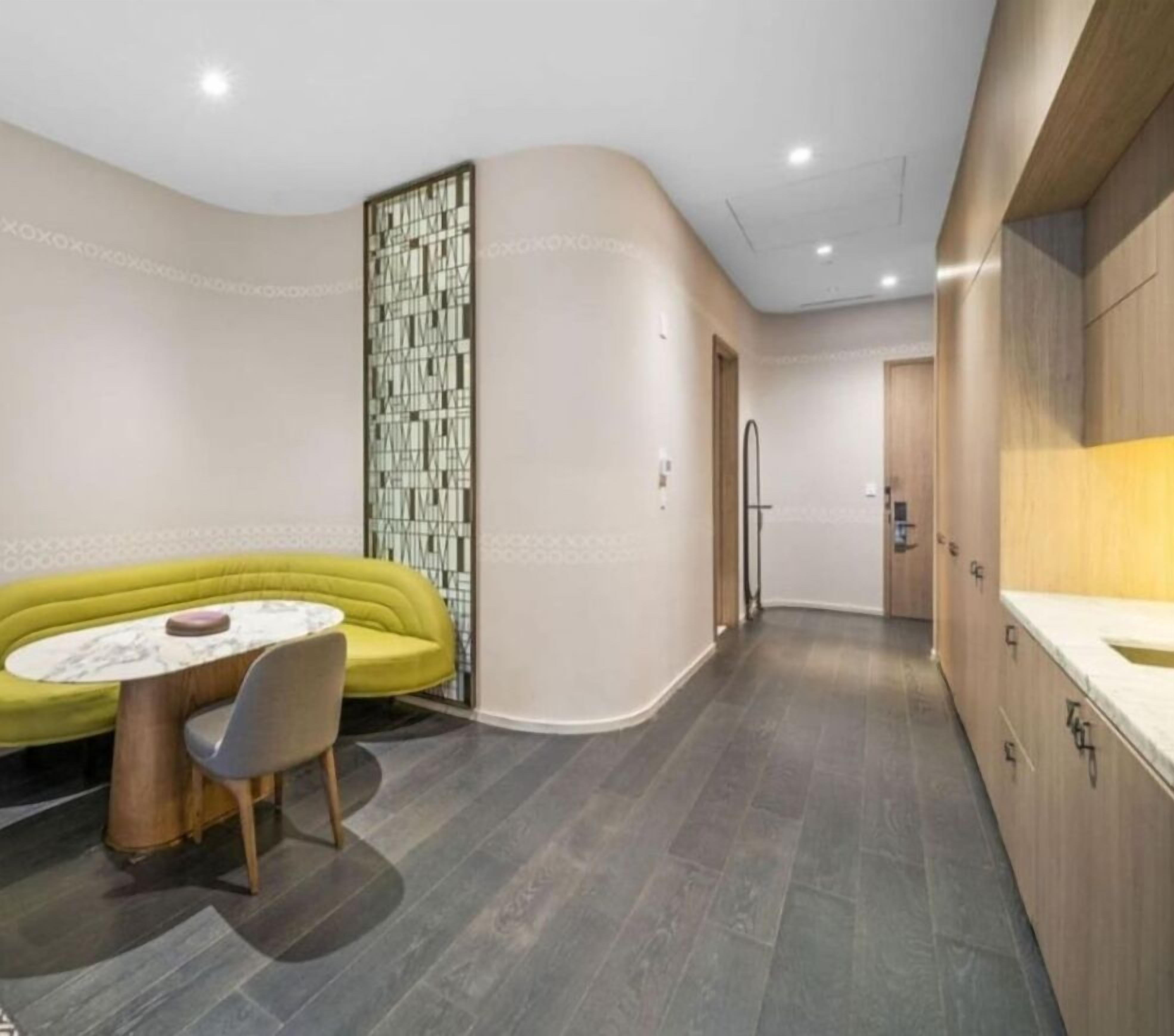 A modern interior with a curved wall, a yellow sofa, a round table, and a minimalist design.