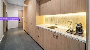 Una cocina moderna con armarios de madera, encimera de mármol y cafetera integrada.