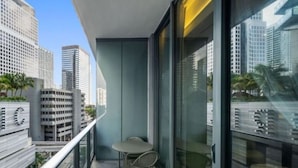 Un balcón con mesa y sillas, con vista a un paisaje urbano con edificios altos.