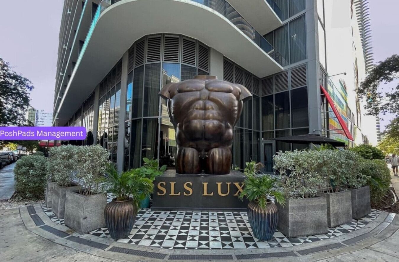 A modern building with a large bronze sculpture in front, labeled "SLS LUX".