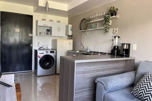 Una cocina compacta con isla integrada, lavadora y cafetera.
