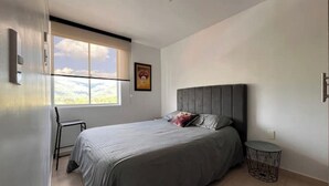 A bedroom with a bed, a chair, a window, and a small round table. - Exotic family getaway (Armenia)