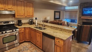 A kitchen with granite countertops, wooden cabinets, stainless steel appliances, and a built-in dishwasher. - Condo Near Snowbasin, 2/2 (Huntsville)
