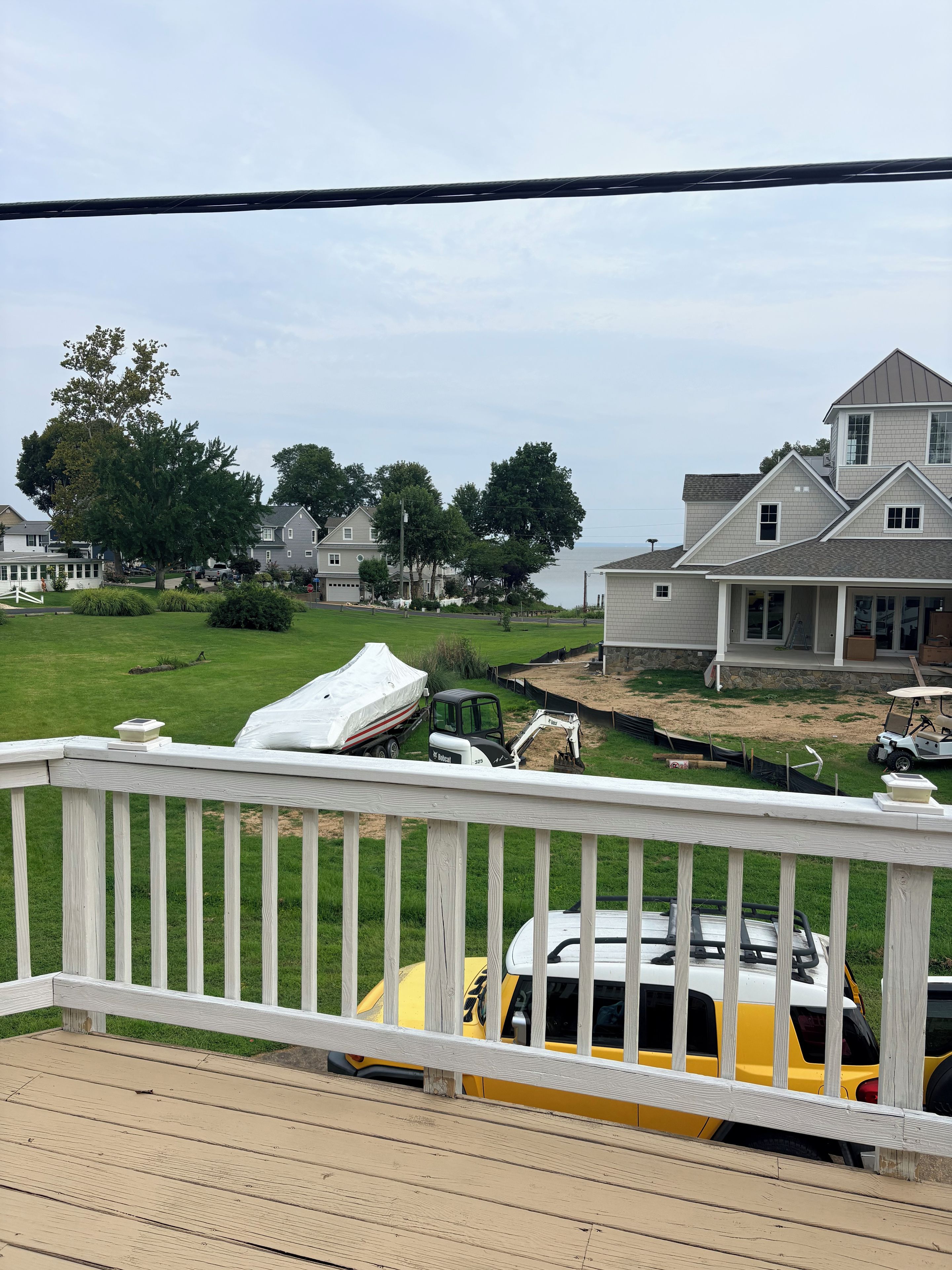 A residential area with houses, a grassy lawn, and a deck with a railing.