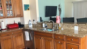A modern kitchen with wooden cabinets, granite countertops, a stainless steel sink, and a built-in dishwasher. - The ShellHunter getaway at Fairview Beach. The perfect place to disconnect. (King George)