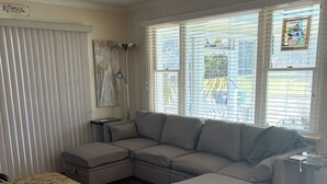 A living room with a sectional sofa, a small table, and a window with blinds. - The ShellHunter getaway at Fairview Beach. The perfect place to disconnect. (King George)