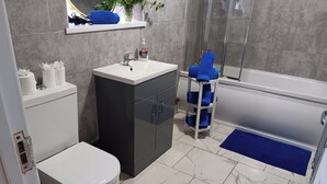 Une salle de bain comprenant des toilettes, un lavabo et un espace douche.