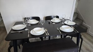 A dining table set with white plates, glasses, and cutlery, surrounded by black chairs and a bench. - 4 Bed-sleeps 9-private Garden-free Parking (Birmingham)