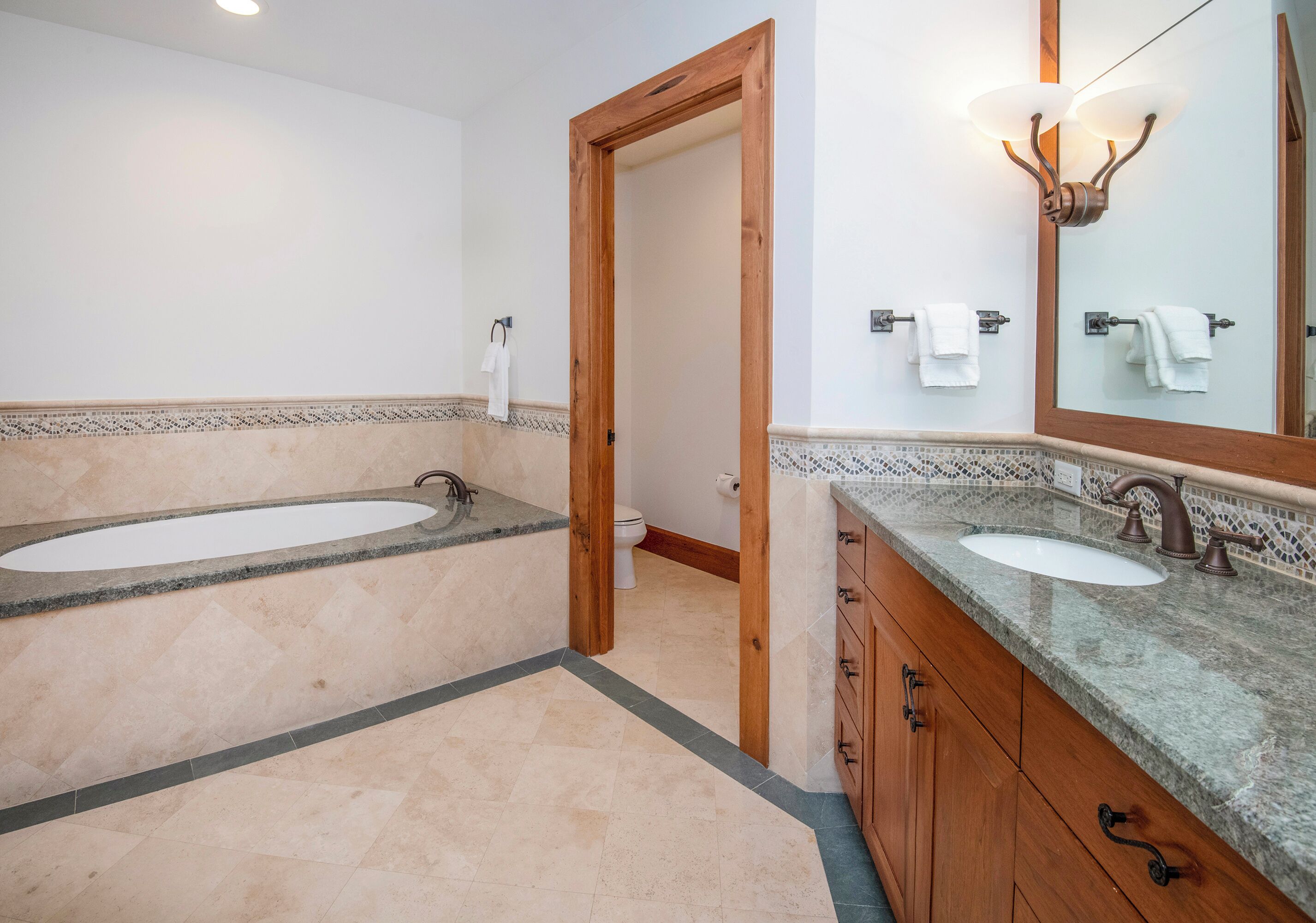 A bathroom with a double sink, wooden cabinets, a large mirror, and a shower area.