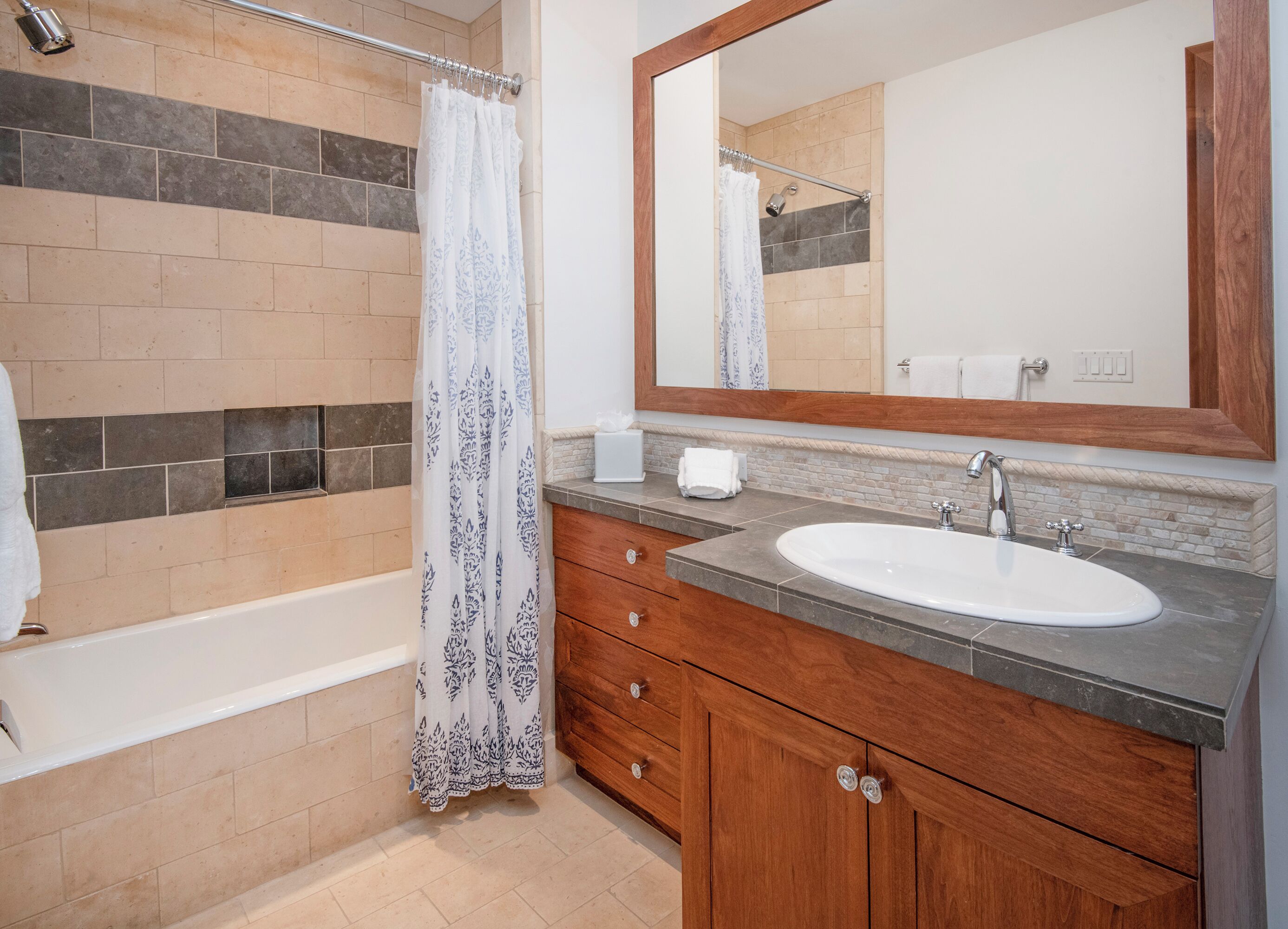 A bathroom with a bathtub, a sink, a mirror, and a shower curtain.