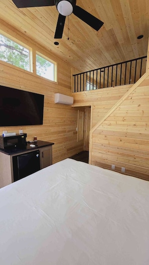 Cozy retreat with a large bed, kitchenette, and flat-screen TV.