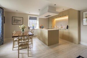 Una cocina moderna con una mesa y sillas de madera, una isla integrada con fregadero y armarios de colores claros.