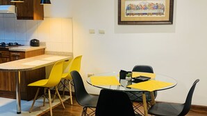 A modern kitchen with wooden cabinets, a countertop, and a dining area with a round table and chairs. - 2 bedroom apartment in cuenca (Cuenca)