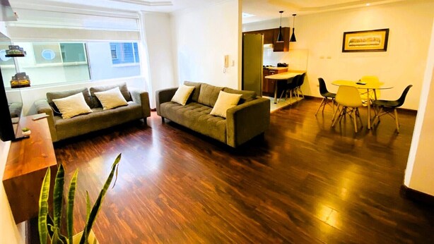 A modern living room with two sofas, a dining area with a yellow table and chairs, and a kitchen in the background. - 2 bedroom apartment in cuenca (Cuenca)