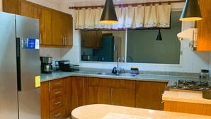 A kitchen with wooden cabinets, a built-in stove, a sink, and a dining area with yellow chairs. - 2 bedroom apartment in cuenca (Cuenca)