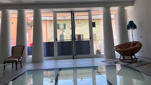 A spacious room with a glass floor, large windows, and a view of colorful buildings outside. - Terra Buona Rooms (Traona)