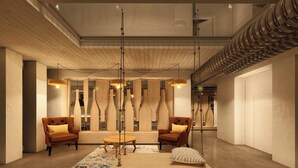 A modern lobby with wooden accents, two leather armchairs, a wooden coffee table, and hanging pendant lights. - Terra Buona Rooms (Traona)