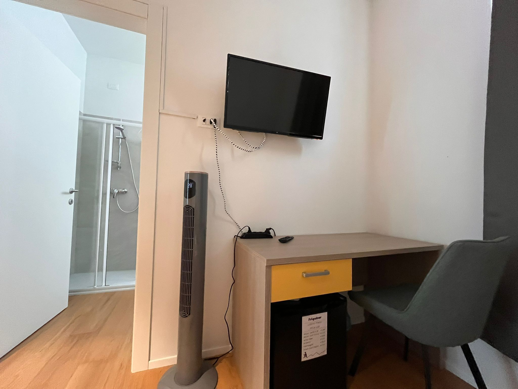 A compact room with a desk, chair, and a mounted TV.