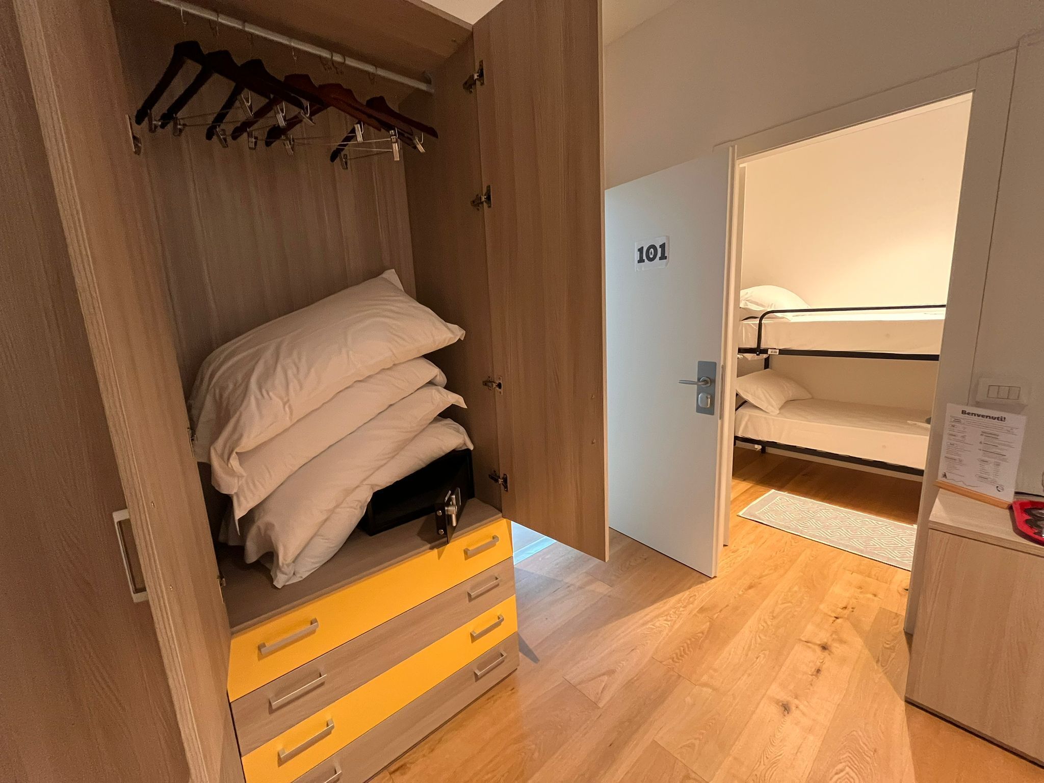 Una camera d'albergo con un armadio in legno, un letto con biancheria bianca e una porta con la scritta '101'.