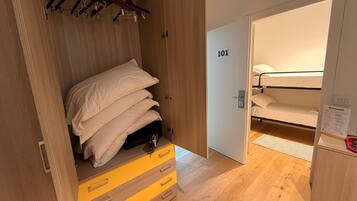 Una camera d'albergo con un armadio in legno, un letto con biancheria bianca e una porta con la scritta '101'.
