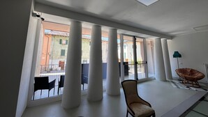 A spacious room with large windows, a chair, and a floor lamp. - Terra Buona Rooms (Traona)