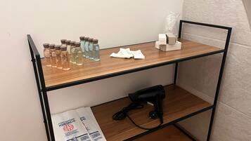 Una estantería de madera con varios objetos, entre ellos botellas, una pequeña caja blanca y un dispositivo negro.