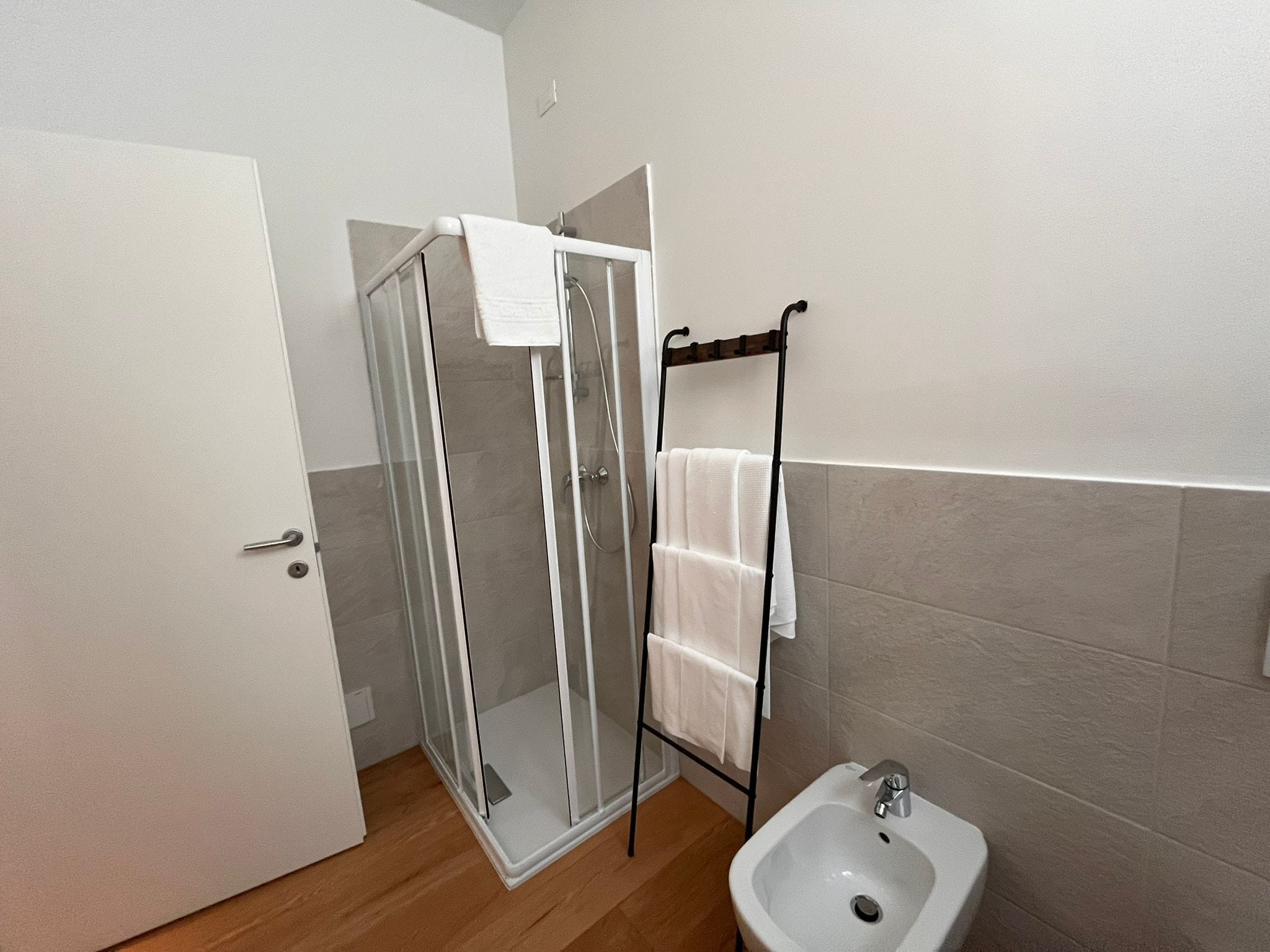 A bathroom with a glass shower enclosure, a white sink, and a towel rack.